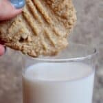 Tahini Cookie being dunked into a tall glass of Milk.