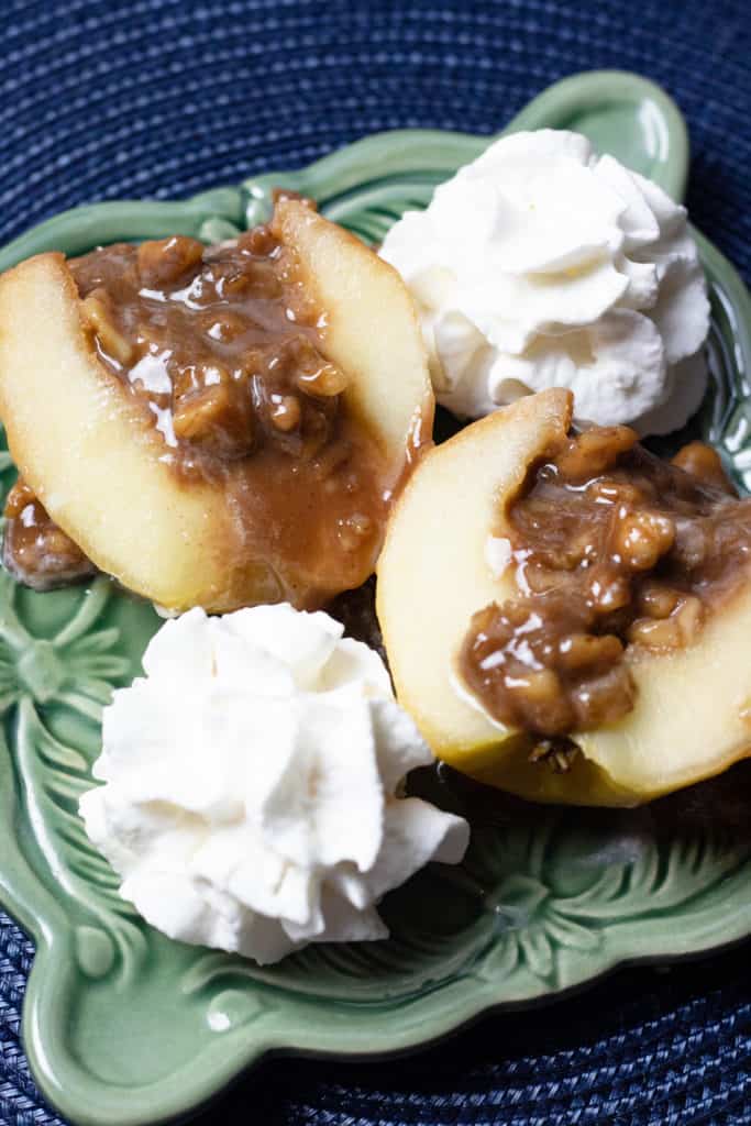 Two halves of poached apples with a caramel walnut center and whipped cream 