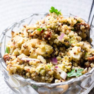 Quinoa salad in a glass bowl mixed with red onions, cheese, and chickpeas.