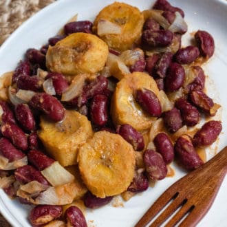 Red beans and plantains on a plate with a wooden fork.