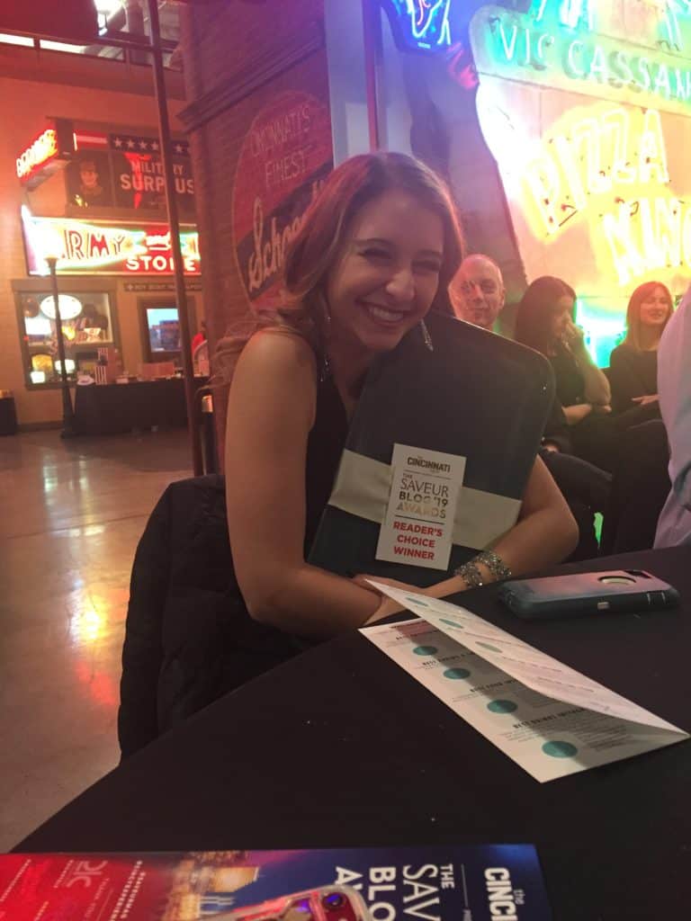 A girl hugging and posing with her award at a table. 
