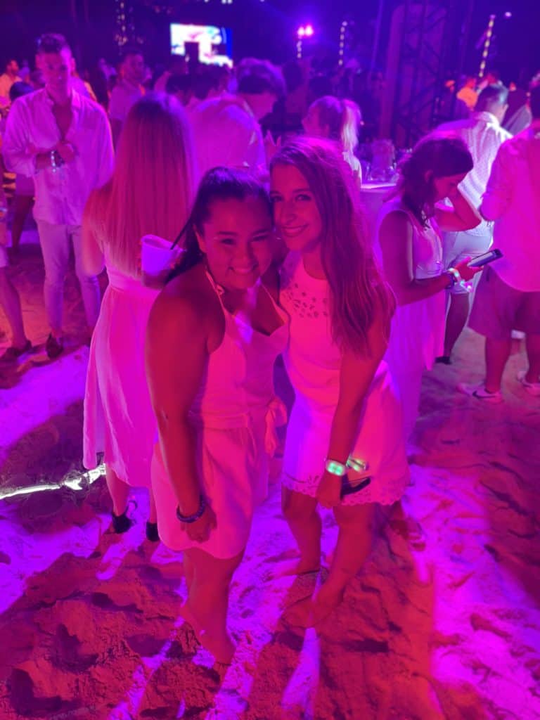 Two girls posing on the beach at nighttime. 