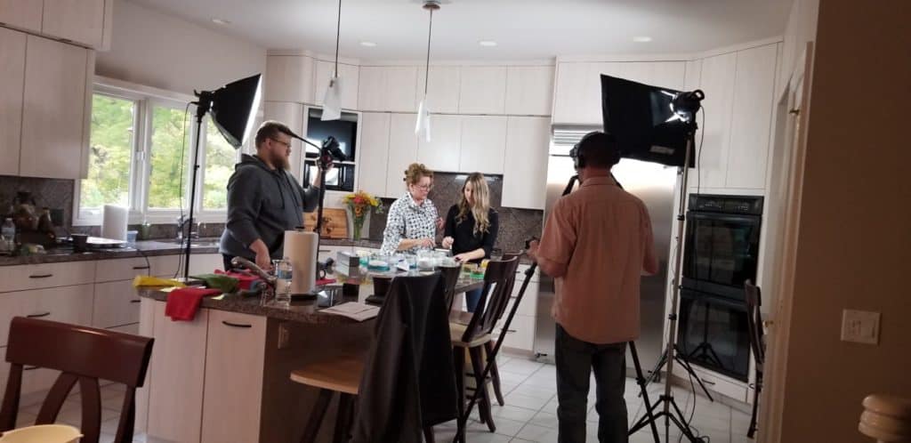 A film crew filming a cooking show in a kitchen. 