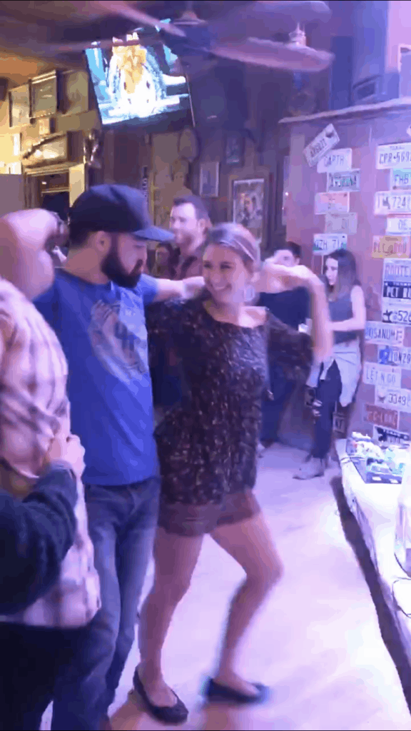 A girl and a guy swing dancing in a bar. 