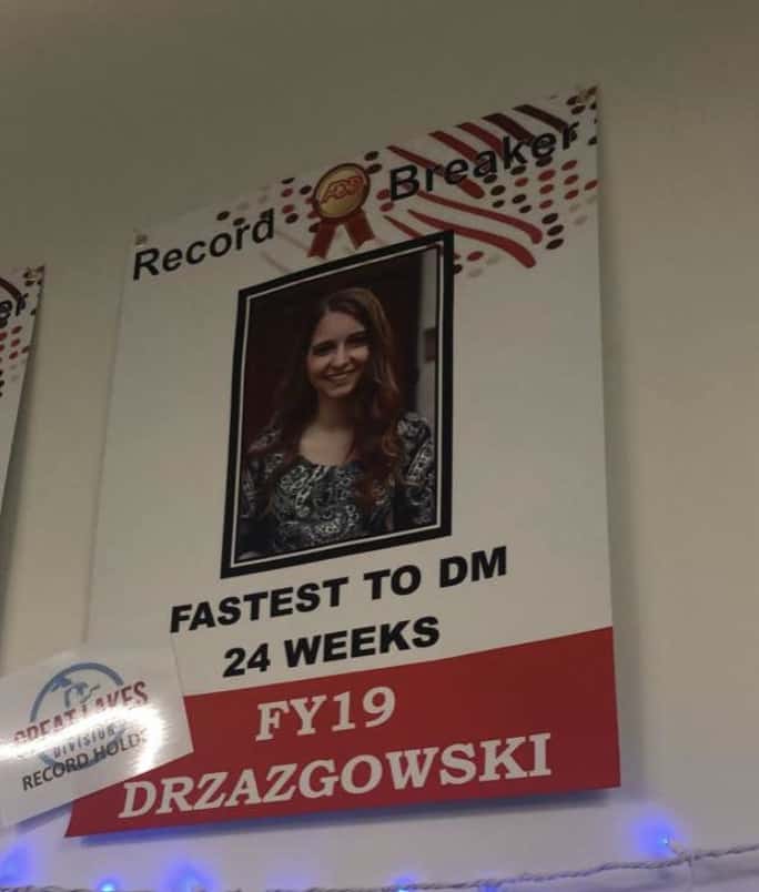 A photo of a poster on the wall with a sign that says "Record Breaker: Fastest to DM 24 Weeks" 