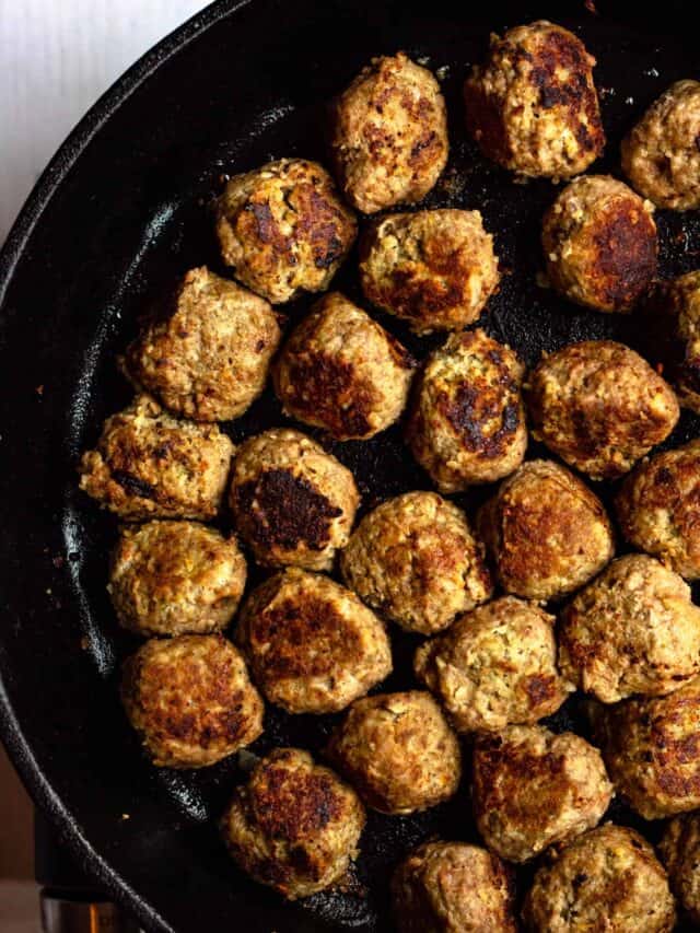 Cast iron skillet filled with browned gluten free meatballs.