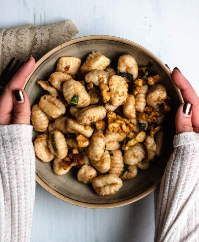hands on a bowl of brown butter gnocchi
