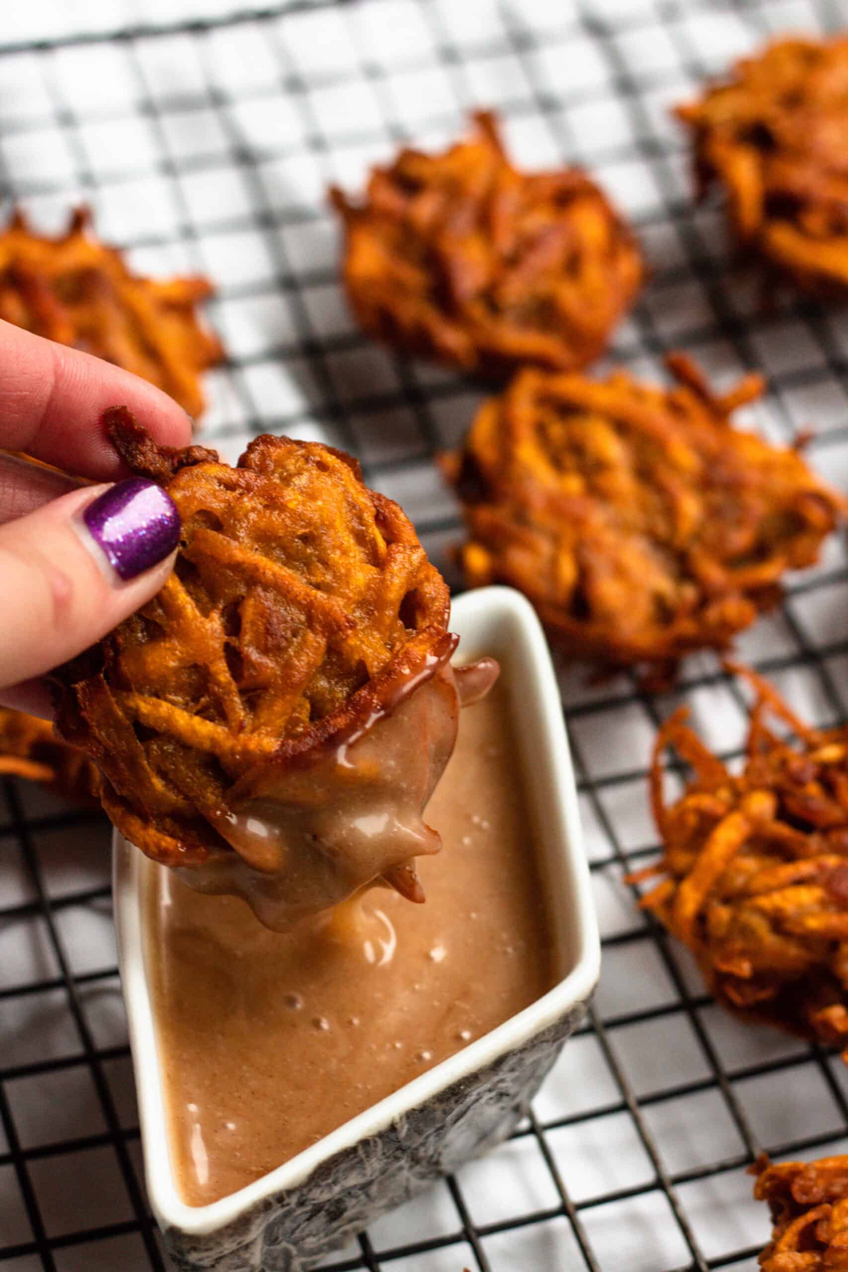Sweet potato fritters being dipped into a honey mayonnaise dip.
