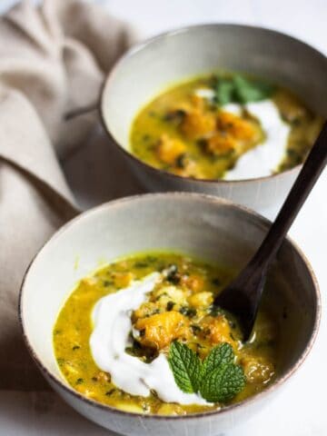 Cambodian fish soup with a drizzle of cream, decorated with a mint leaf.