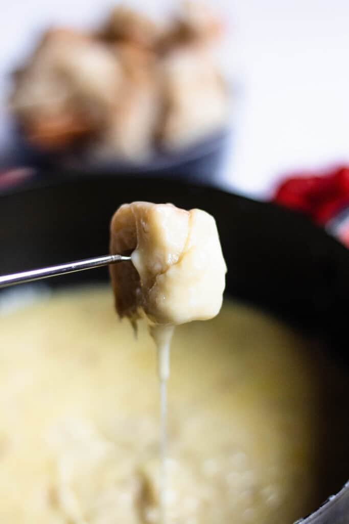 bread being dipped in cheese fondue