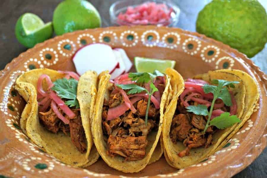 Yucatan slow cooked pork in 3 taco shells on a brown plate 