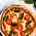 Pinterest image of an overhead view of a full Margherita Pizza with basil leaves and tomatoes.
