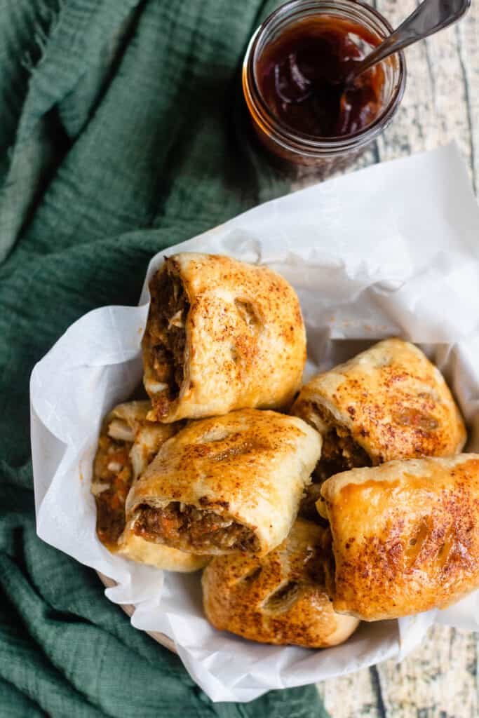 bowl of Australian sausage rolls with barbecue sauce in the background 