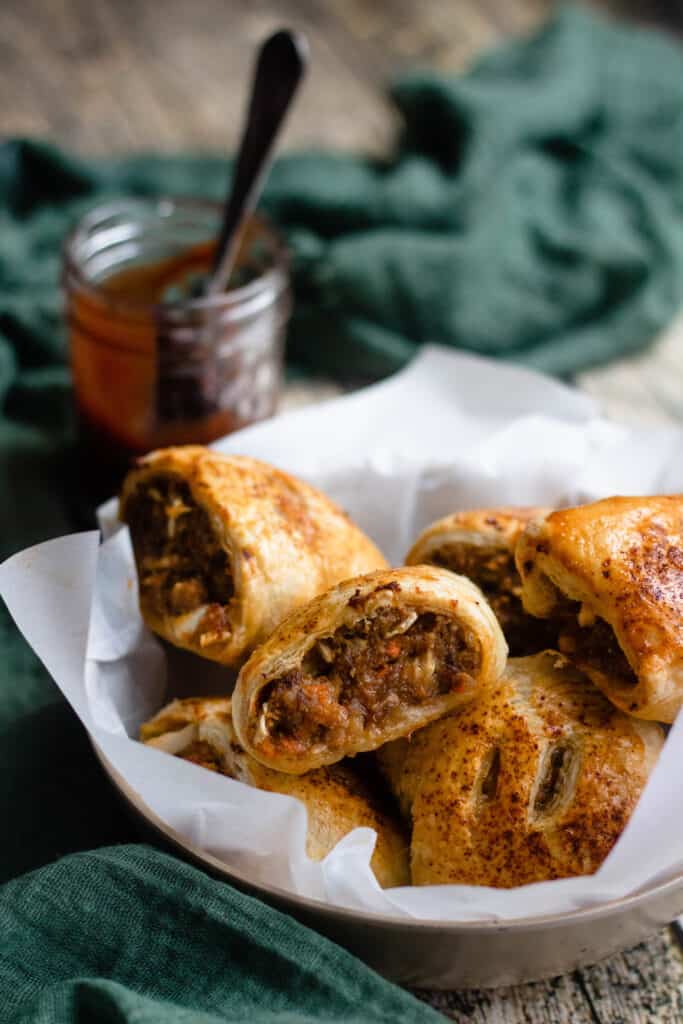 Sausage roll recipe in a bowl with barbecue sauce in the back 