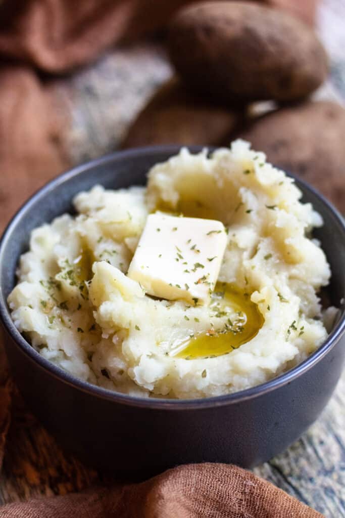 Instant Pot Mashed Potatoes with potatoes behind 