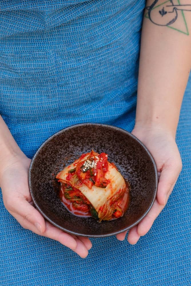A woman's hands holding a bowl of Kimchi 