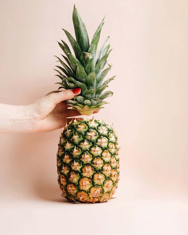 Pineapple with top being taken off