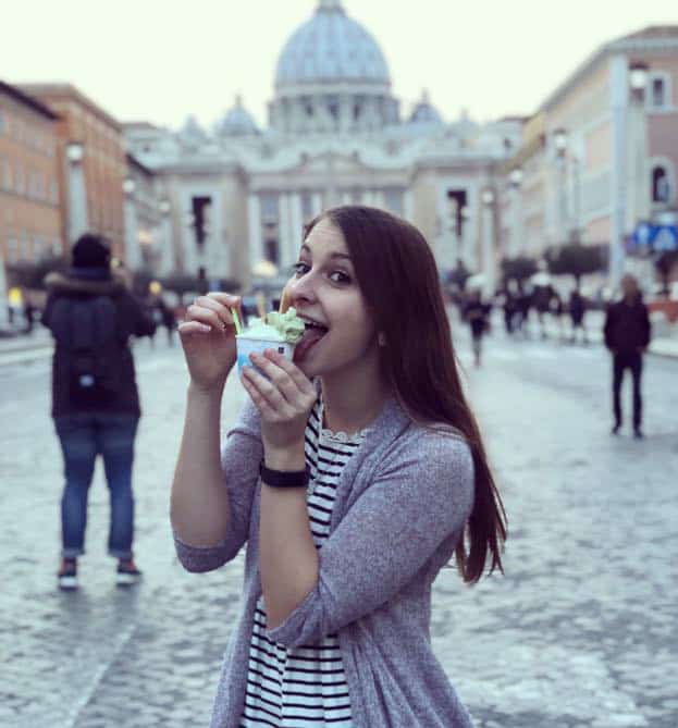 Alexandria in Italy enjoying a bite of gelato in a busy street.