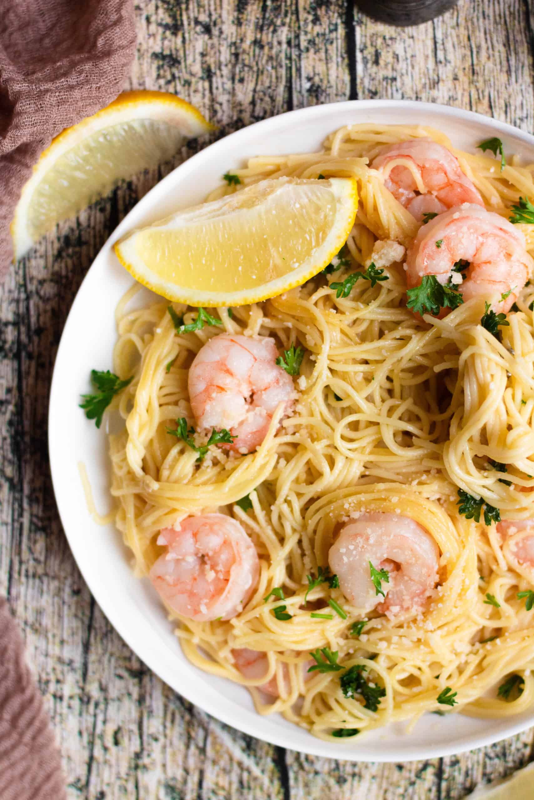 Close up of bowl with Shrimp Scampi and a lemon wedge garnished on the side.