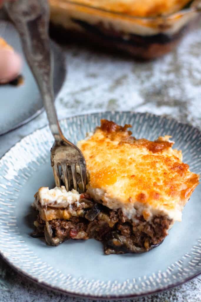 Cypriot Food: Moussaka on a blue plate being eaten by a fork