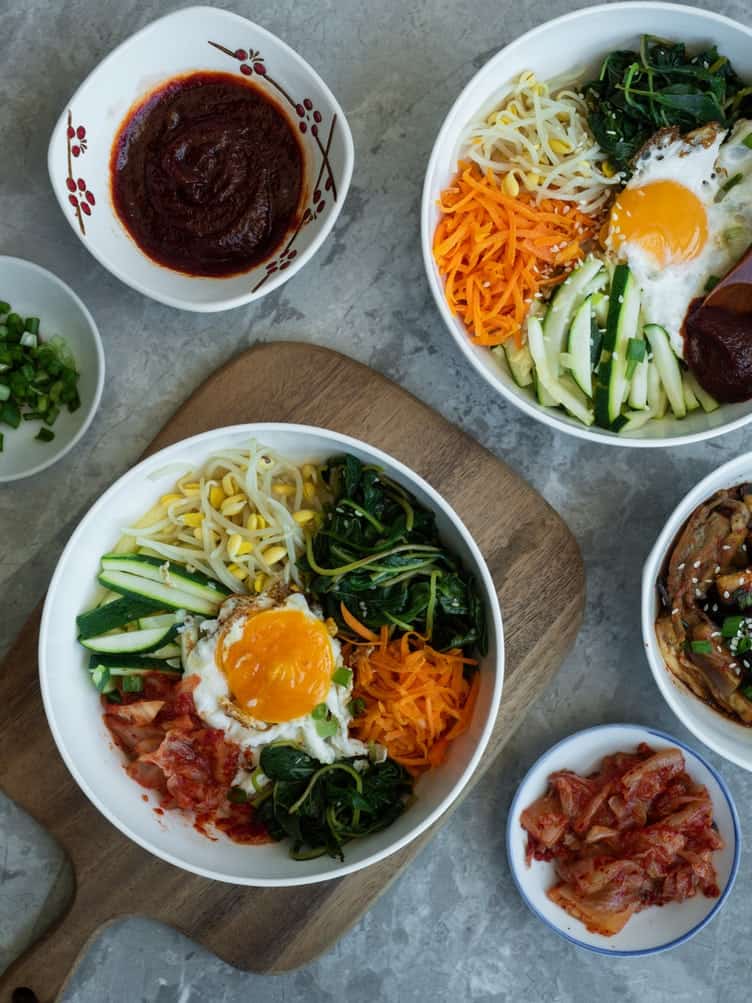 Overhead shots of bimbimbap with sauces, vegetables, and eggs