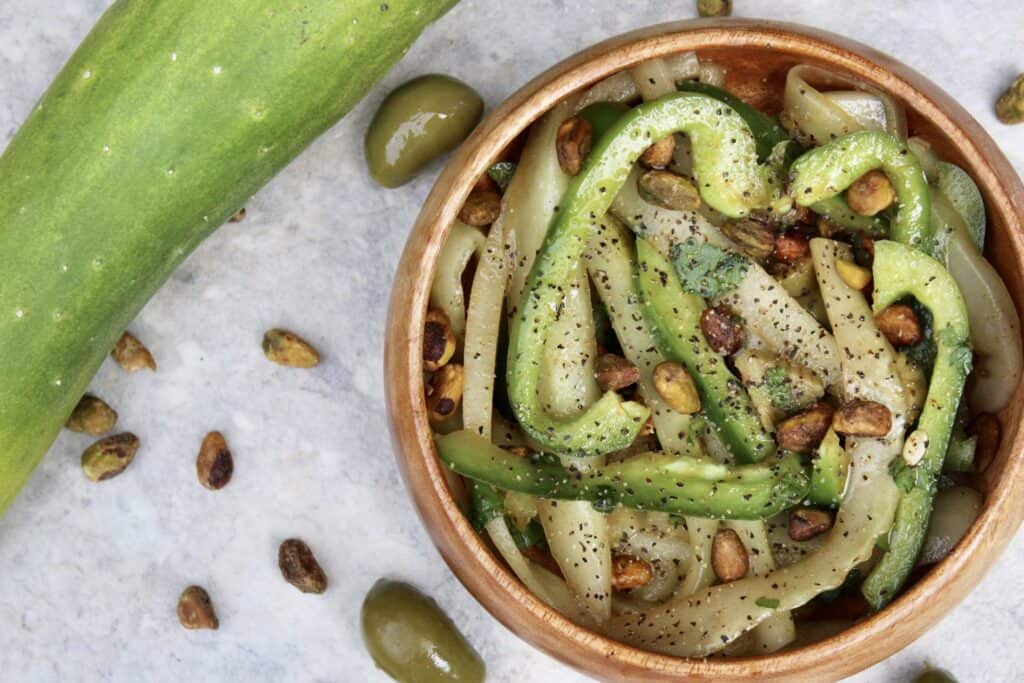 Overhead view of cucumber salad with pistachios and olives