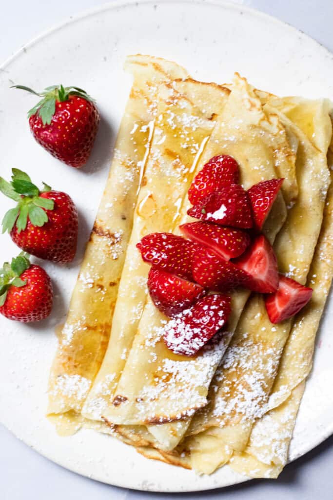 Honey butter crepes with cut strawberries and honey on top 