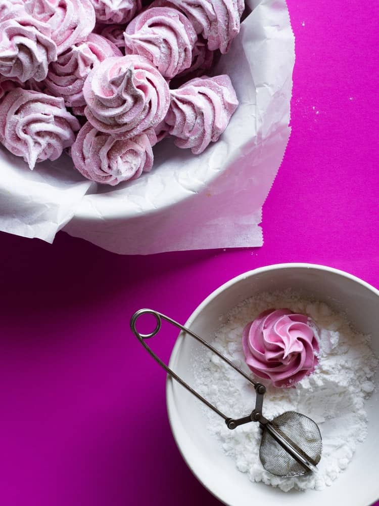 Bright magenta background with homemade marshmallows and powdered sugar