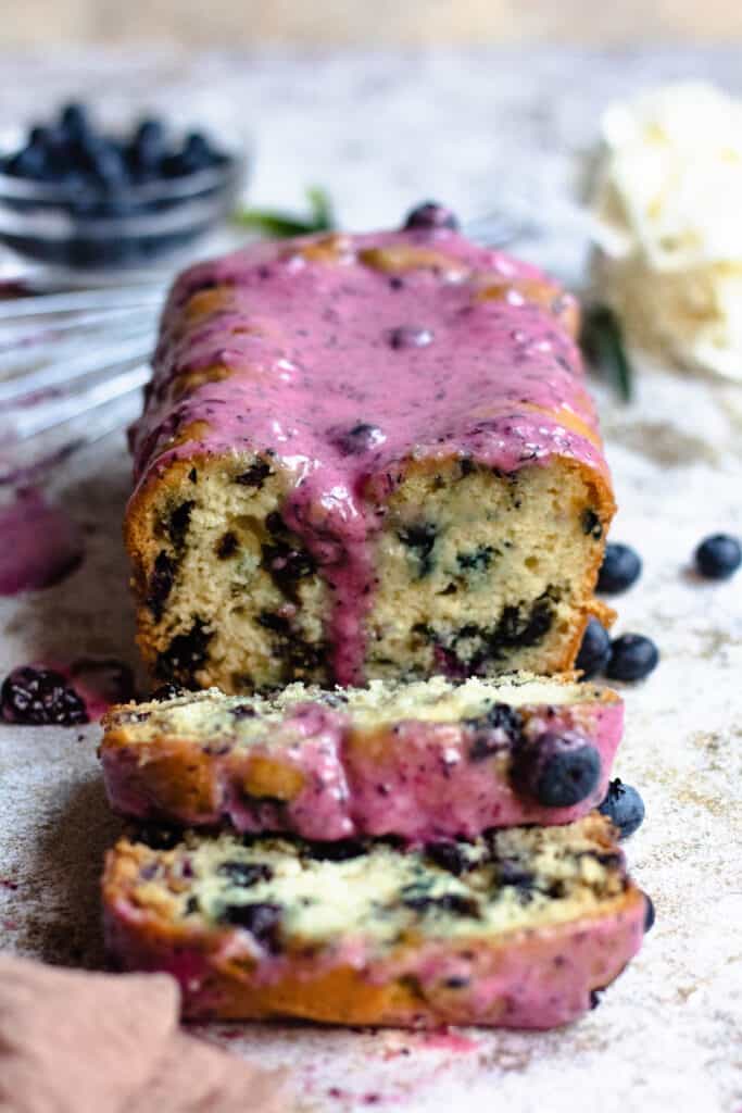 Blueberry bread with glaze dripping and slices cut 