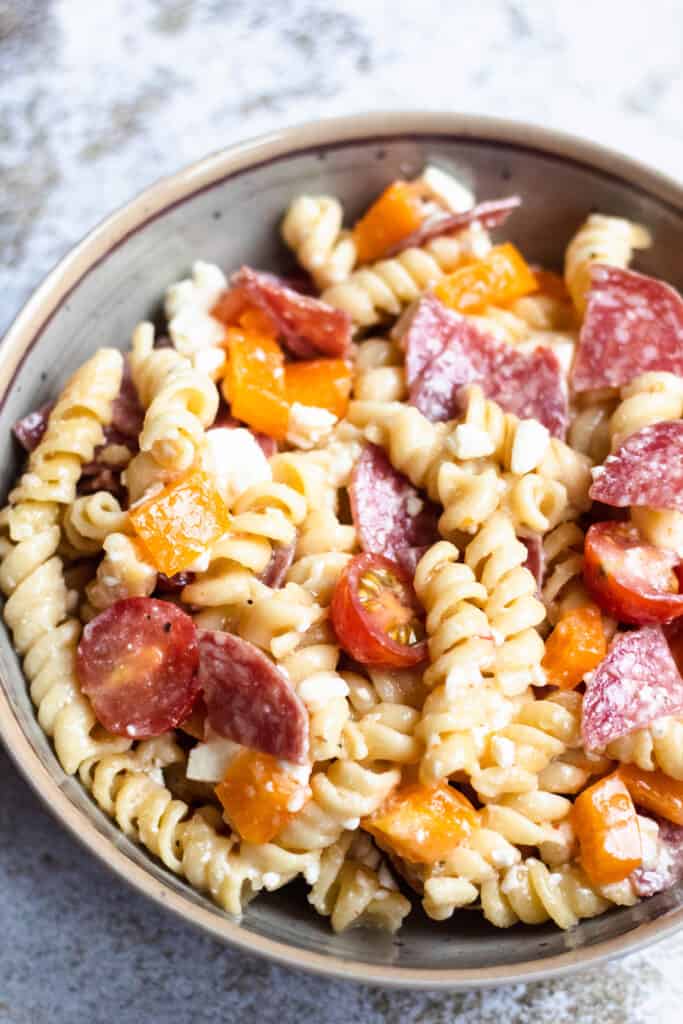 Overhead view of easy pasta salad on a concrete background. Rotini pasta with peppers and salami
