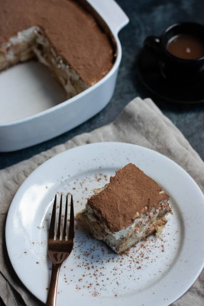Photo of tiramisu on a plate with a golden fork 