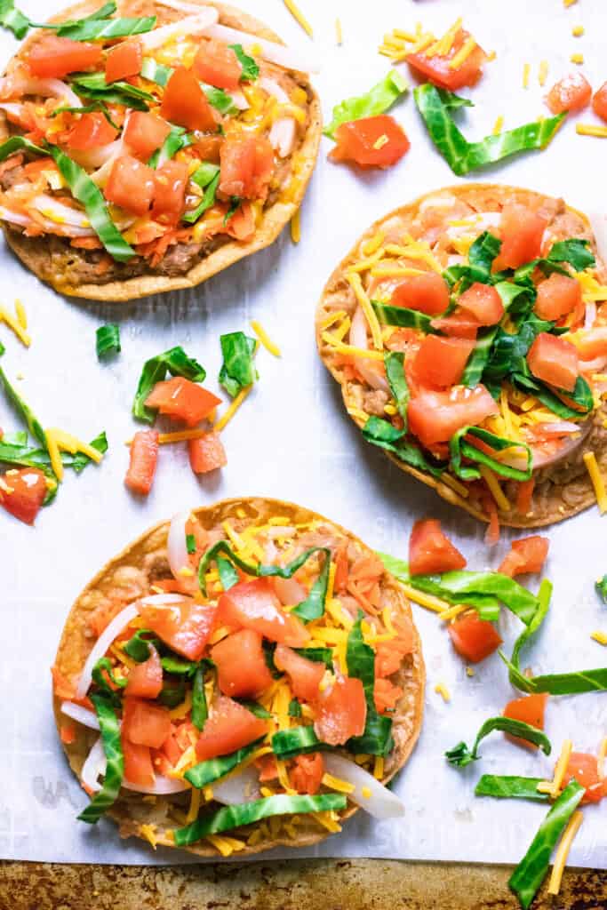 overhead of 3 garnaches/tostadas on parchment paper and a cookie sheet
