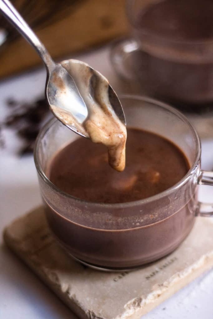 Mug of hot chocolate with a spoon dripping in cheese