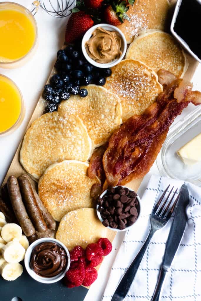 Overhead view of pancake breakfast board with orange juice