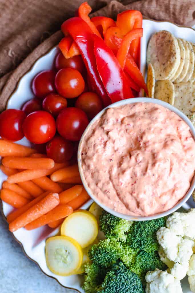 Close up overhead of dip with vegetables and crackers on the side