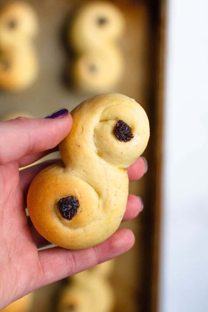 A hand holding an S buns with raisins in the swirls