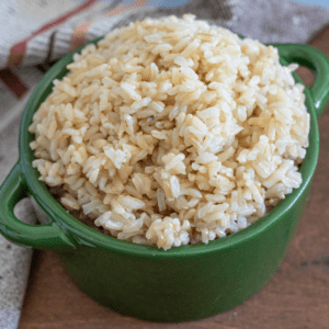 A small pot filled with cooked brown rice sitting next to a cloth napkin.