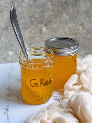 Jars of spiced ghee with cheesecloth next to the jars.