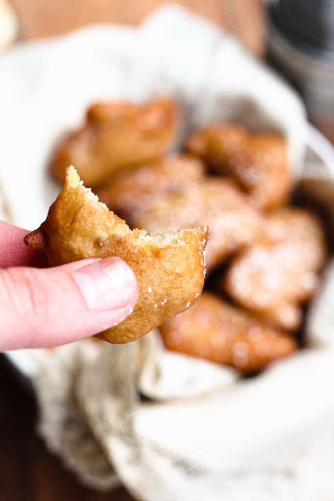 Hand holding a banana fritter with a bite taken 