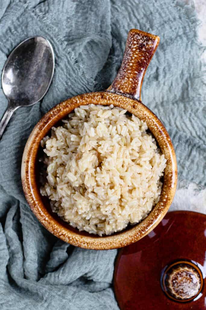 Brown rice in a ceramic dish with spoon and linen 