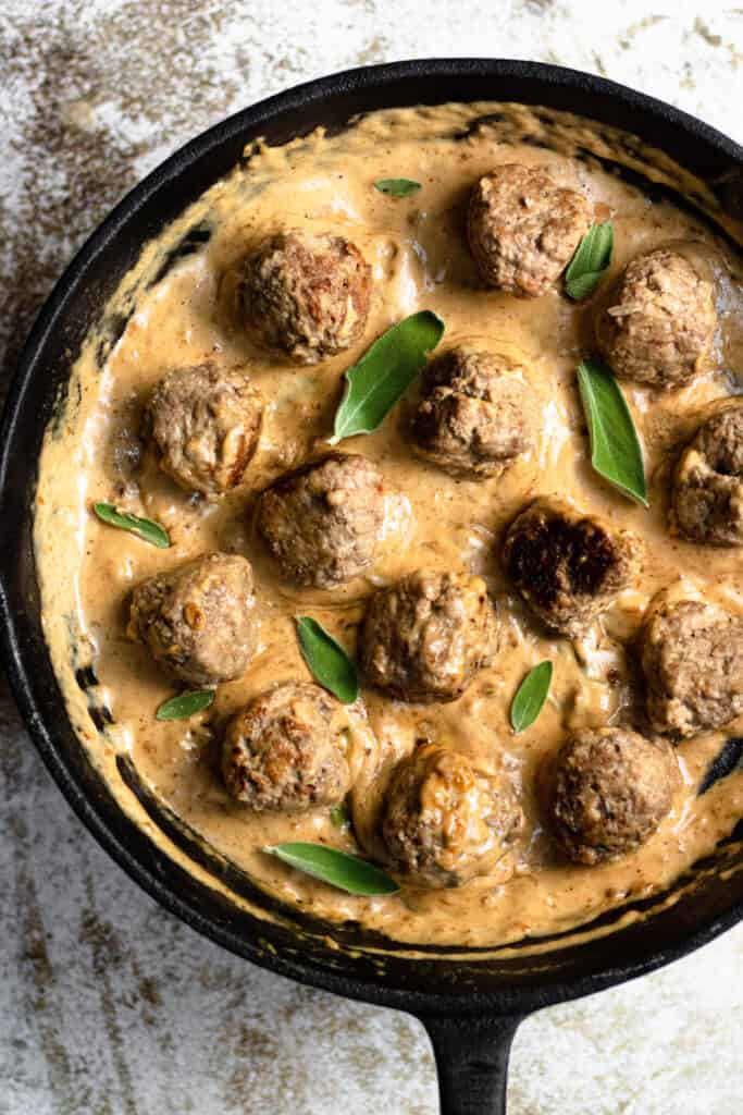 Frikadeller in a cast iron skillet with sage leaves