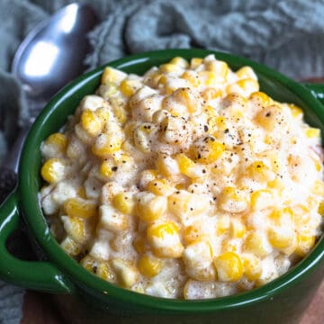 Creamed corn in a serving crock topped with black pepper.