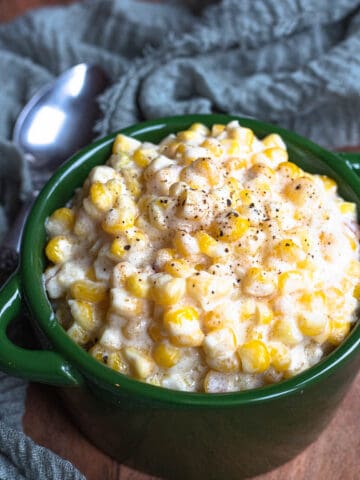 Creamed corn in a serving crock topped with black pepper.
