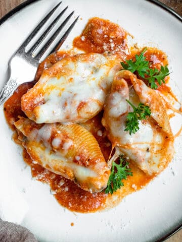 Stuffed shells on a plate sprinkled with parmesan cheese and filled with risotto.