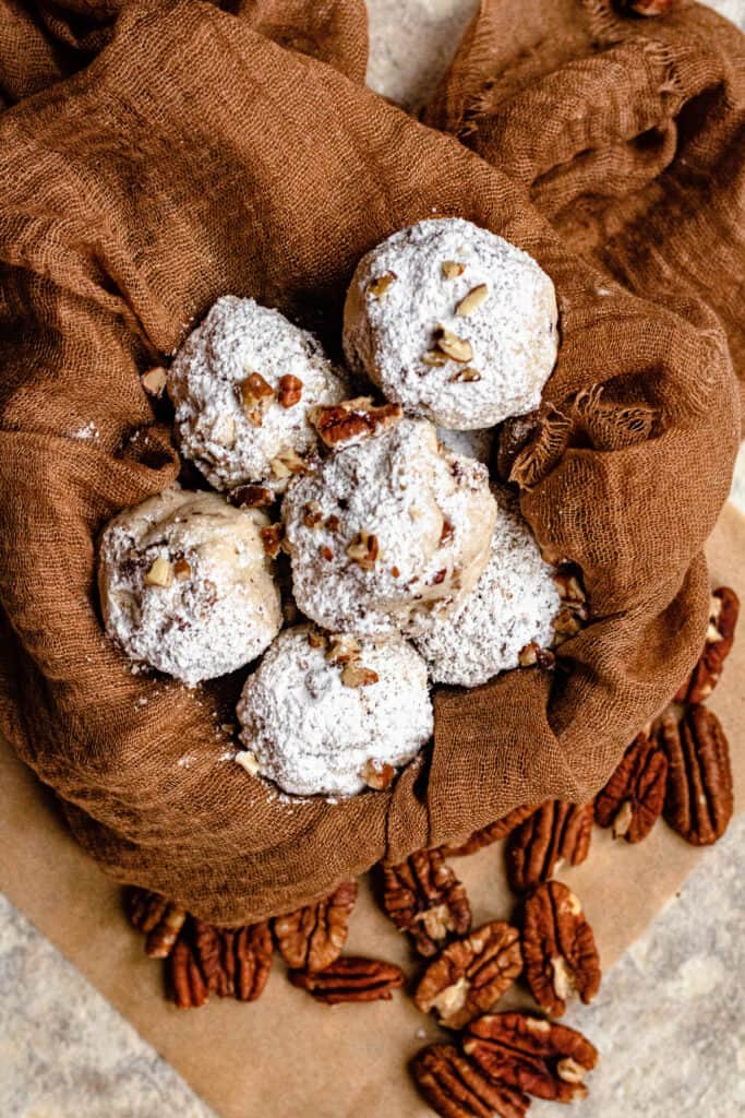 Bowl of Pecan Snowball Cookies with pecans around the bowl 