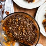 Sweet potato casserole in a glass bowl with servings taken out.