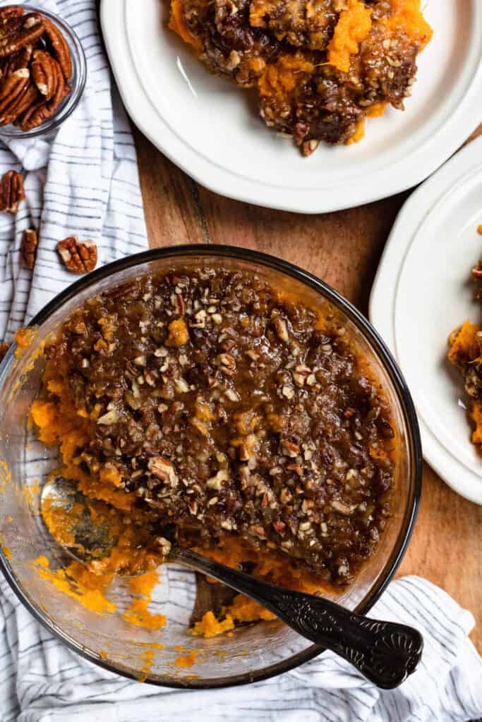 A bowl of sweet potato casserole with a scoop taken out and a spoon in the glass bowl. 