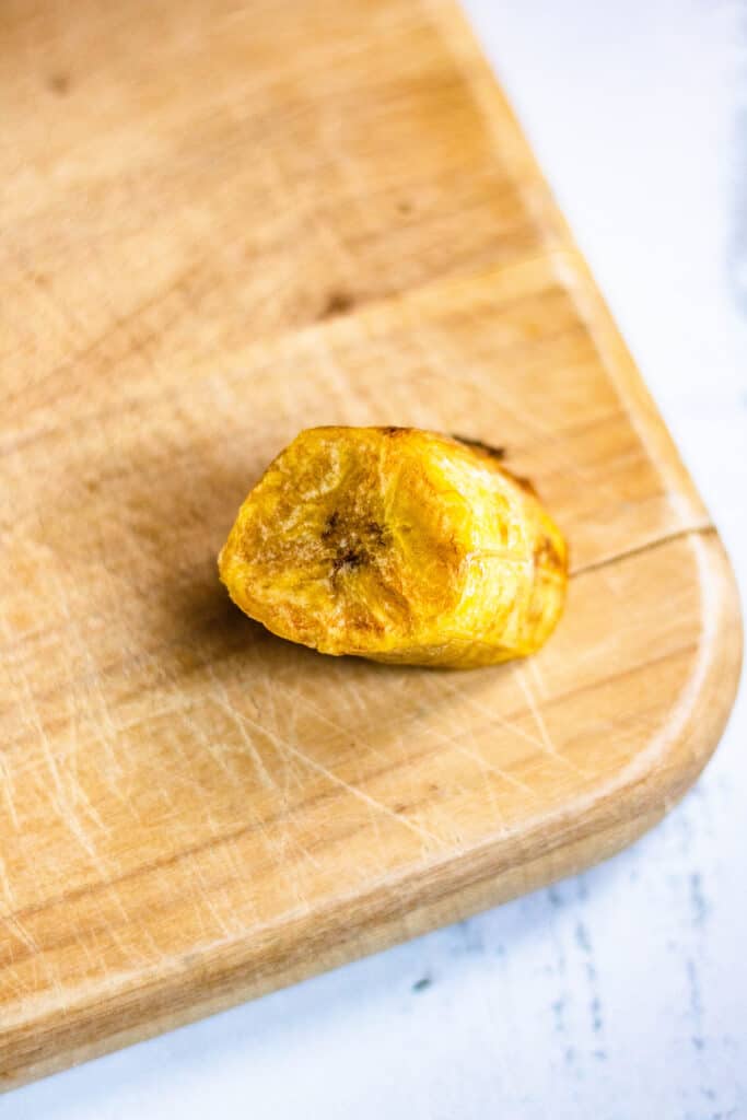A small, fried plantain waiting to be smashed with a glass