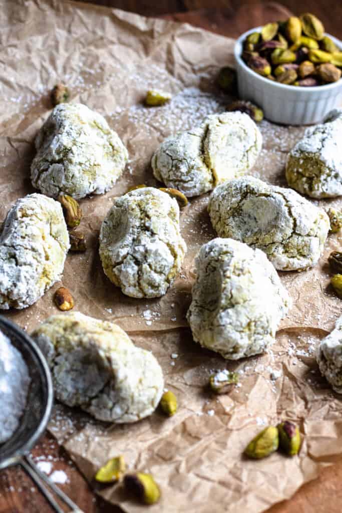 Cookies on brown parchment paper with pistachios all around 