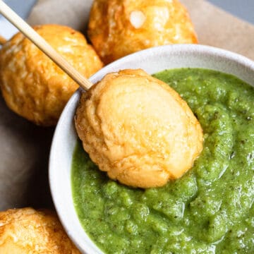 Dipping fried eggs in a green sauce.